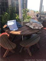 Round wood patio table with items on top and two of the four benches visible
