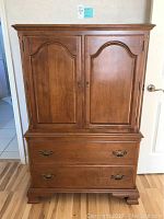 Front view showing overall dresser armoire with two upper cabinet doors and two large drawers beneath.