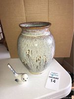 Photo of the pottery vase upright next to the ceramic bird figurine, showing glaze and carved details.