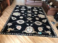 Top view of the full area rug laid flat on a hardwood floor showing floral pattern and border details.