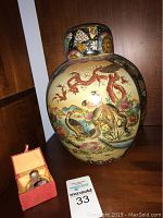 Front view of large hand-painted Royal Satsuma style vase showing detailed birds and landscape design with small glass bottle in box beside it