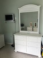 Front view of white dresser with attached arched mirror, all drawers closed