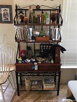 Front view of metal and wood baker's rack displaying three shelves and two drawers.