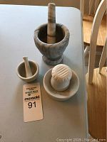 Top view of three crushers: two marble mortar and pestle sets and one ceramic juicer with ridged bowl
