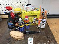 Photo showing assorted car cleaning supplies including lubricants, rubbing compound, gloves, rags, brush, bungie cords, and cleaning buffer.
