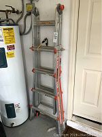Folded ladder stored against wall near water heater, showing overall form and size.