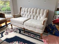 Front view of the upholstered loveseat showing tufted backrest, wooden frame, and floral upholstery pattern.