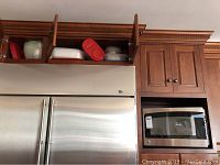 Microwave and plastic containers atop refrigerator and kitchen cabinet