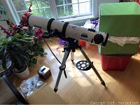 Full view of white optical tube mounted on tripod with accessory tray