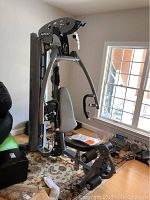 Assembled gym machine showing overall frame, seat and leg developer on rug near window