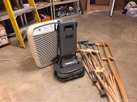 Photo showing Kenmore Hepa Filter 295 air purifier, Epic Floor Pro floor buffer, and three pairs of crutches in a garage setting.
