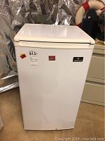 Front and top view of white ACME mini fridge with ABSCOLD logo and stickers, showing minor wear and dirt.