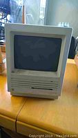 Front view of the Apple Macintosh SE computer showing the CRT screen and dual 3.5-inch floppy disk drives.