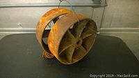 Two vintage steel pulley wheels shown from side angle on black surface, highlighting rust and age marks.