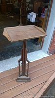 Photo of mid-century wooden pedestal stand showing the full height, rectangular top with raised edges, and base details.
