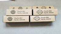 Four new-in-box Harley Davidson spark plugs, two with plug number 6R12, part number 32362-04X, and two with plug number 5R6A, part number 32342-04.