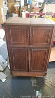 Front view of dark wooden Art Deco portable bar cabinet with closed top and double doors.