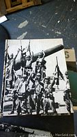 Front cover of a hardcover book featuring World War II soldiers raising arms around a large artillery gun
