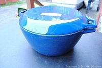 Side view of blue enamel cast iron Dutch oven showing shape, lid, and handles.