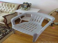 Photo of gray plastic patio chair and wood tile decorative table with chips and paint wear