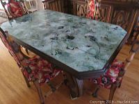 Top view of glass tabletop showing mottled green-gray floral pattern with scratches.