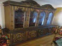 Full front view of the two-piece wood veneer china cabinet with glass doors and ornate carved details.