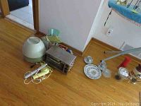 Photo showing green dome-shaped massager, Sunbeam toaster oven, yellow and white vintage hair dryers, heating pad, and part of ironrest board.