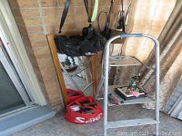 Photo showing two black purses hanging and a red bag on floor, with a step ladder and mirror in background. Purses show wear and damage.