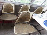 Six vintage metal frame chairs with vinyl and floral upholstery seats and backs, arranged around a room corner.