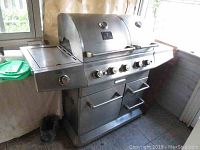 Side view of the stainless steel gas BBQ grill showing the side shelf and control knobs.