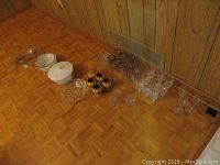 Photo of all glassware and serveware items arranged on the floor showing the variety of plates, dishes, cups, and glasses