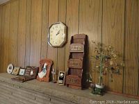 Wall-mounted octagonal clock, wooden organizer for letters, bills, and misc, framed plaques, ceramic goose figurine, and religious plaques on wooden wall paneling.