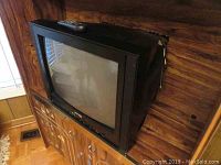 Diamond 21 inch CRT TV sitting on wooden cabinet, remote control resting on top, showing front and sides clearly.