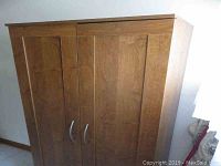 Front view of three-door faux wood pantry with curved silver handles.
