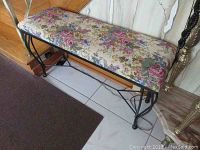 Side view of the metal bench showing the floral upholstered seat and metal frame with curved legs
