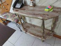 Full view of the hall table showing the top and bottom marble shelves and ornate metal legs