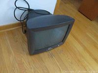 Front and side view of black Dell CRT monitor with curved display, no base included, placed on floor near wall with visible power cord.