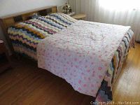 Full view of the wood bed frame with colorful bedding showing the bed's size and design.