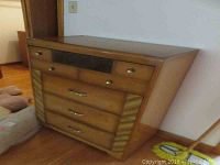 Front view of the wood dresser showing three drawers with different metal handles and angled sides.