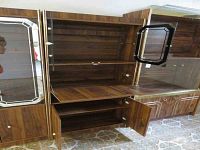 Front view of full faux wood cabinet showing glass upper display doors opened, internal wooden shelves, and lower storage compartment doors opened, highlighting interior compartments and shelf space.