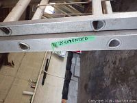 Close-up photo of aluminium extension ladder showing markings '12' 24' extended' on the side rail.