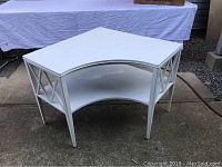 Full view of the white corner coffee table showing lattice sides and curved lower shelf