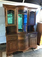 Front view of entire vintage china hutch showing upper bevelled glass cabinets, curved central glass display, drawers and lower cabinets.