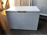 White chest freezer with lid closed, showing exterior condition and lock.