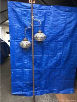 Full view of the vintage swag lamp with two hanging glass shades against a blue backdrop.