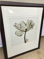 Framed flower picture leaning upright on floor, showing full image, frame, and matting