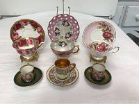 Photo showing six demitasse tea cups with matching saucers, various floral and gold designs, different styles and colors.