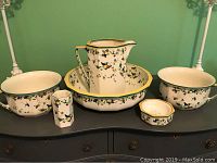 Entire Royal Doulton wash set displayed on dark surface with six pieces including basin, jug, 2 chamber pots, toothbrush holder, and soap dish, showing floral pattern and yellow trim.