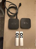 Photo of two Apple TV units with their remotes and power cord