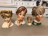 Four ceramic lady head vases displayed on table